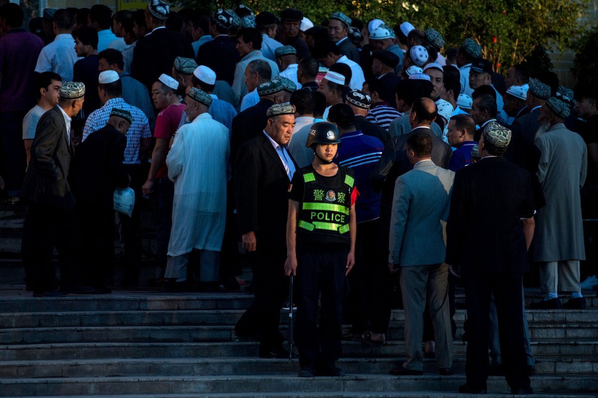 Um policial em serviço enquanto muçulmanos chegam à oração matinal de Eid al-Fitr na mesquita Id Kah em Kashgar, Xinjiang, China, em 26 de junho de 2017 (Johannes Eisele / AFP / Getty Images)