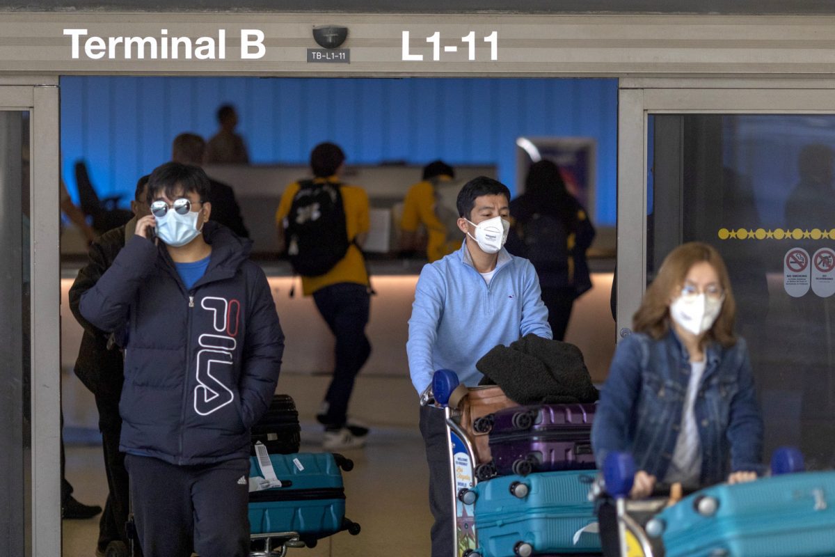 Os viajantes chegam ao Terminal Internacional Tom Bradley do LAX com máscaras médicas para se proteger contra o novo surto de coronavírus em Los Angeles, Califórnia, em 2 de fevereiro de 2020 (David McNew / Getty Images)