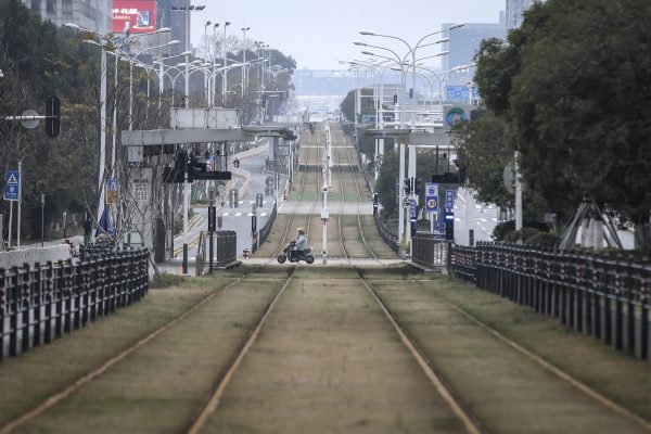 Um residente anda de moto por uma rua vazia em Wuhan, província de Hubei, China, em 7 de fevereiro de 2020 (Getty Images)