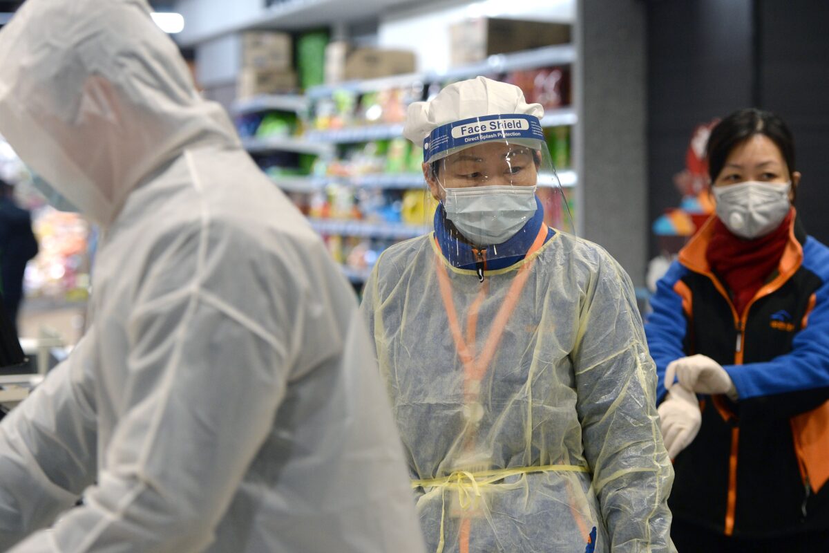 Um membro da equipe que usa máscara e traje de proteção trabalha em um supermercado em Wuhan, o epicentro do surto de um novo coronavírus, na província central de Hubei, na China, em 10 de fevereiro (STR / AFP via Getty Images)