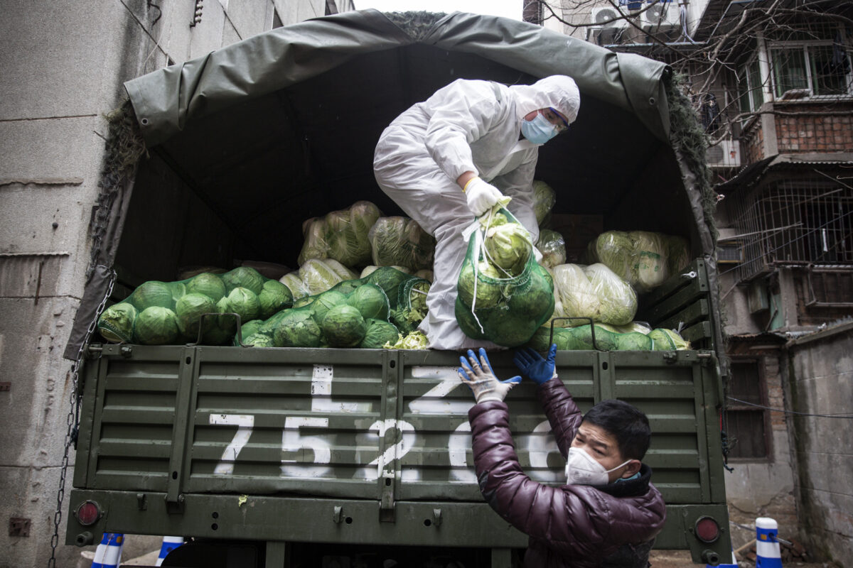 Um funcionário usa uma máscara protetora enquanto carrega legumes de caminhões em um hospital em Wuhan, China, em 10 de fevereiro de 2020 (Stringe / Getty Images)