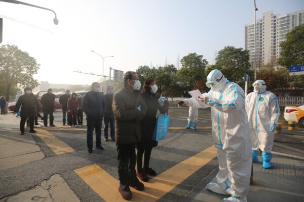 Profissionais de saúde (vestem roupas de proteção) revisam pacientes que se recuperaram do coronavírus COVID-19 quando retornam para exames adicionais em um hospital em Wuhan, China, em 14 de março de 2020 (STR / AFP via Getty Images)