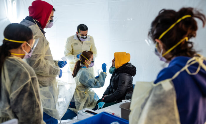 Médicos examinam funcionários do hospital com sintomas semelhantes à gripe para a COVID-19 em tendas de campanha para classificar os possíveis pacientes com COVID-19 do lado de fora antes de entrarem na área principal do departamento de emergência do Hospital St. Barnabas, no Bronx, na cidade de Nova Iorque, em 24 de março de 2020 (Misha Friedman / Getty Images)