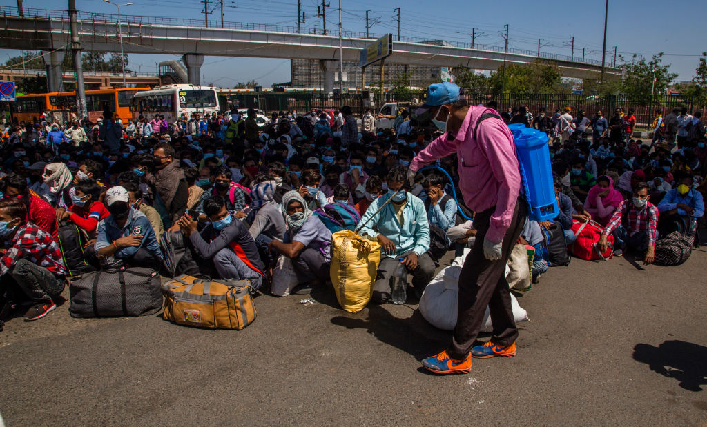 Um trabalhador de saúde indiano pulveriza desinfetante na bagagem de trabalhadores e trabalhadores migrantes, juntamente com suas famílias presas na capital nacional, enquanto esperam para embarcar em ônibus para retornar às suas aldeias nativas, enquanto o bloqueio nacional continua por causa do coronavírus altamente contagioso (COVID-19 ) em Ghaziabad, em 29 de março de 2020, nos arredores de Nova Délhi, na fronteira com o estado de Uttar Pradesh (Yawar Nazir / Getty Images)