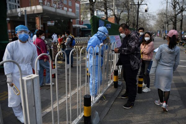 A equipe do hospital (esquerda) registra pacientes na calçada do lado de fora de um hospital infantil em Pequim, China, em 31 de março de 2020 (GREG BAKER / AFP via Getty Images)