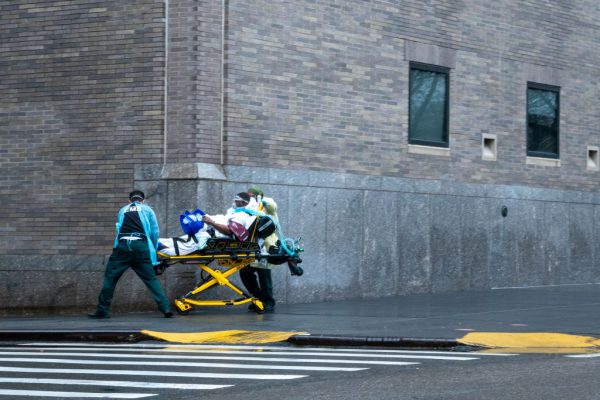 Trabalhadores dos serviços de emergência transportam um paciente na calçada do lado de fora do Hospital Mount Sinai em 13 de abril de 2020 na cidade de Nova Iorque (David Dee Delgado / Getty Images)