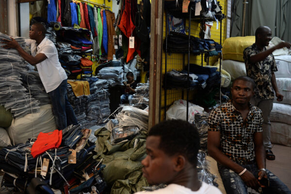 Lamine Ibrahim (I), da Guiné, trabalha enquanto seu filho de quatro anos olha para sua loja em um mercado atacadista de roupas em Guangzhou, na China, em 26 de agosto de 2013 (STR / AFP via Getty Images)