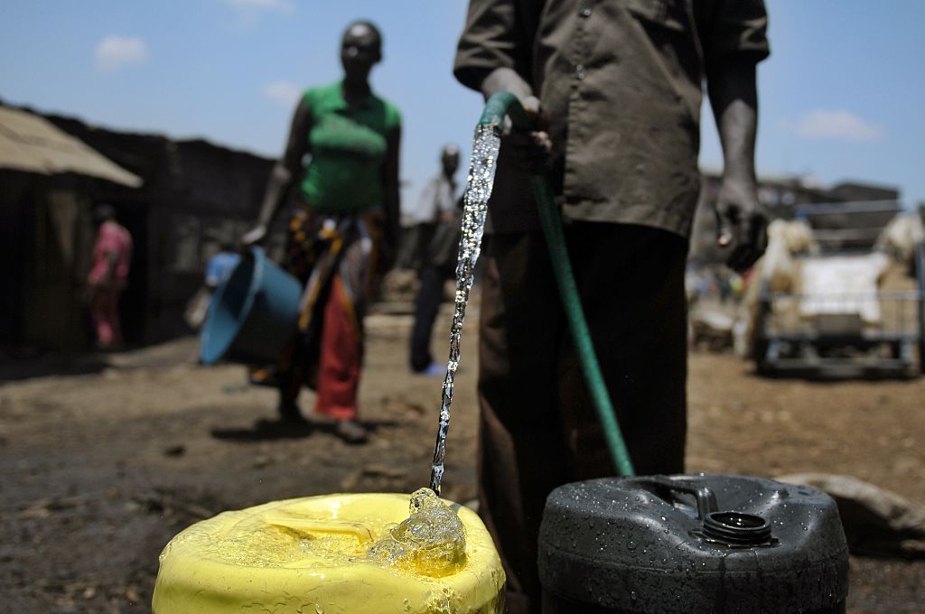 Um fornecedor de água coleta água em jerrycans para vender na favela de Mathare, Nairobi, em 22 de março de 2012, onde a escassez de água continua a ocorrer no Dia Mundial da Água (Tony Karumba / AFP via Getty Images)