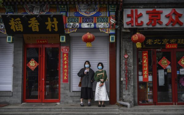 Mulheres chinesas usam máscaras enquanto aguardam do lado de fora de lojas e restaurantes fechados perto da Cidade Proibida em Pequim, China, em 19 de abril de 2020 (Kevin Frayer / Getty Images)