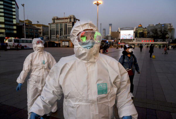 Pessoas usam máscaras faciais e roupas de proteção enquanto chegam à Estação Ferroviária de Pequim em 13 de março de 2020 (Kevin Frayer / Getty Images)