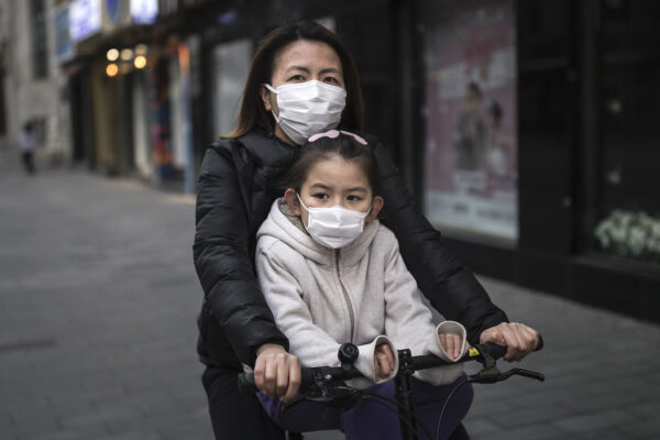 Uma mãe usa máscara enquanto anda de bicicleta com sua filha em Wuhan, província de Hubei, China, em 11 de abril de 2020 (Getty Images)