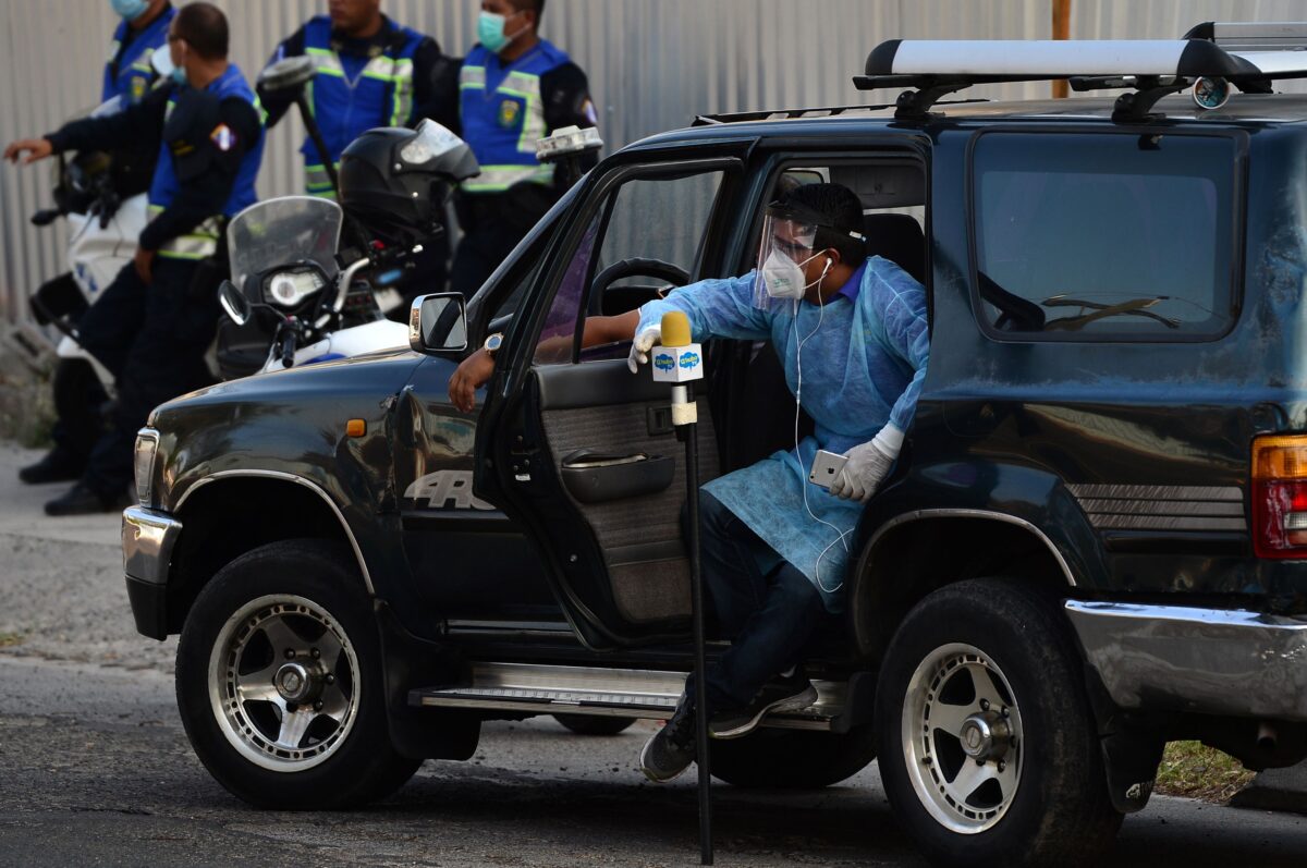 Um jornalista veste um traje de proteção contra propagação COVID-19 enquanto aguarda a chegada dos restos mortais do ex-presidente hondurenho Rafael Leonardo Callejas de Atlanta, EUA, na Base da Força Aérea de Tegucigalpa, em 9 de abril de 2020 (Orlando Sierra / AFP / Getty Images)