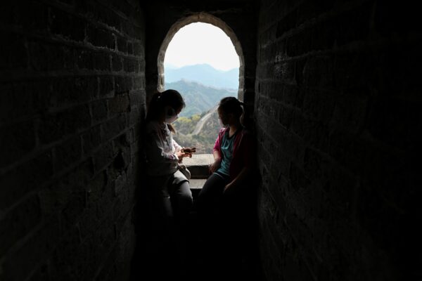 Duas crianças usando máscaras descansam durante sua visita à Grande Muralha da China, em Pequim, em 18 de abril de 2020 (Wang Zhao / AFP via Getty Images)