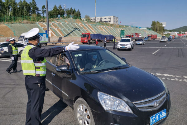 Um policial orienta um motorista de carro a registrar informações em uma saída da estrada em Jilin, China, em 13 de maio de 2020 (STR / AFP via Getty Images)