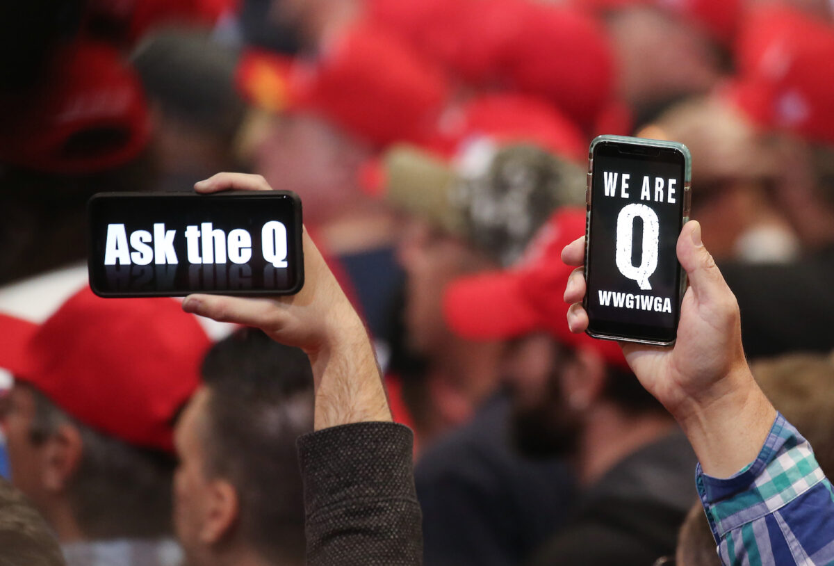 Pessoas seguram smartphones com mensagens relacionadas ao QAnon em exibição, em um comício em Las Vegas, em 21 de fevereiro de 2020 (Mario Tama / Getty Images)