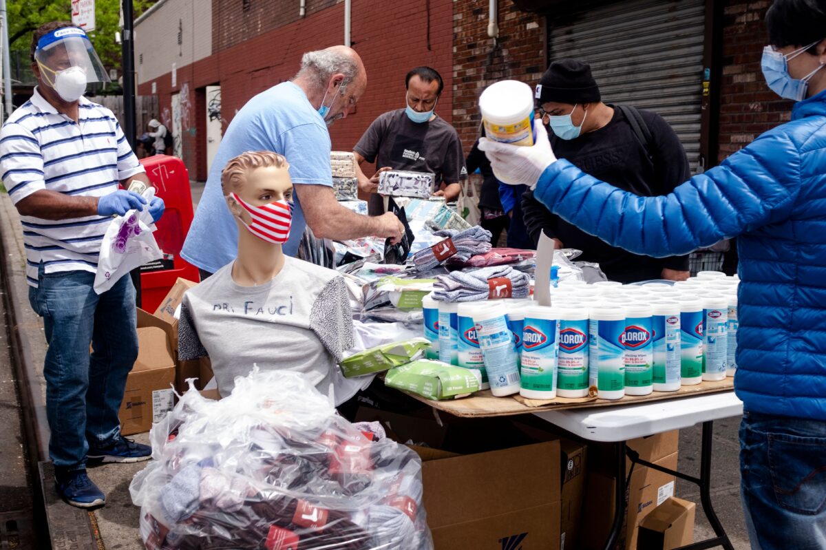 Um homem vende máscaras faciais e lenços de desinfecção em uma mesa ao lado da rua no bairro de Elmhurst, Queens, na cidade de Nova Iorque, Nova Iorque, em 18 de maio de 2020 (Johannes Eisele / AFP via Getty Images)