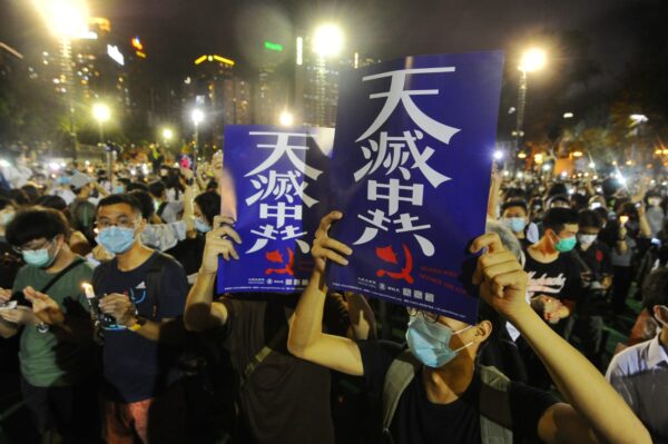 As pessoas seguram cartazes com as palavras “Os céus destruirão o Partido Comunista Chinês” em uma vigília no Victoria Park, Hong Kong, em 4 de junho de 2020 (Song Bilung / The Epoch Times)