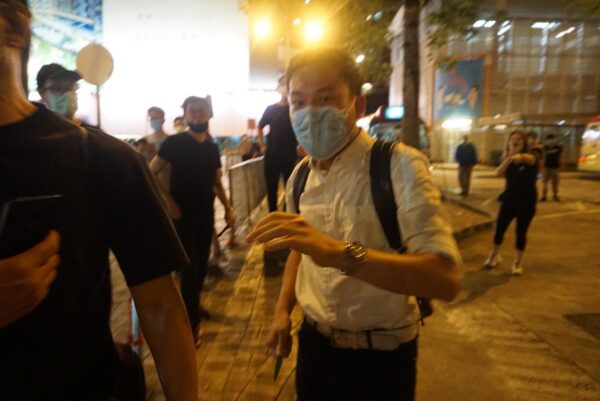 Um homem ameaça um funcionário do Epoch Times e outros cidadãos com sua faca em Hong Kong, em 12 de junho de 2020 (Jerry / The Epoch Times)