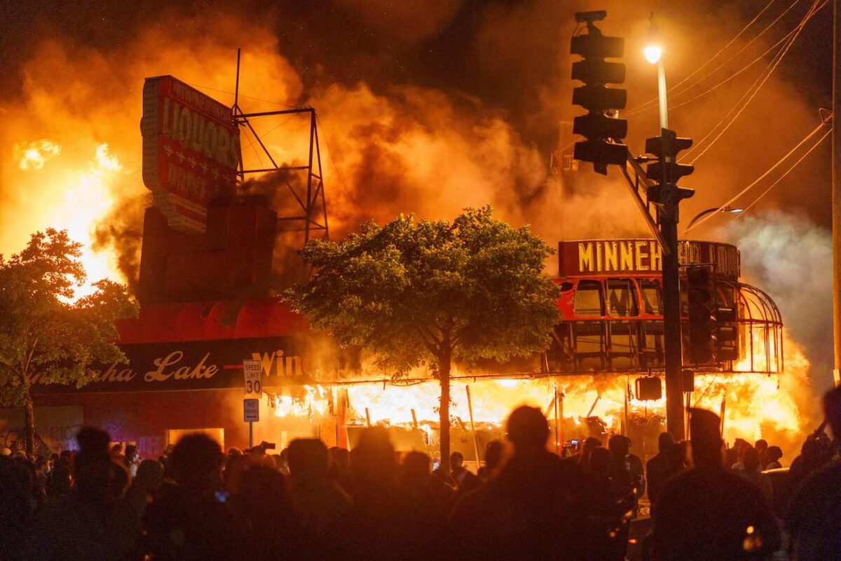 Os manifestantes se reúnem em frente a uma loja de bebidas em chamas perto da Terceira Delegacia de Polícia em Minneapolis, Minnesota, em 28 de maio de 2020 (Kerem Yucel / AFP via Getty Images)