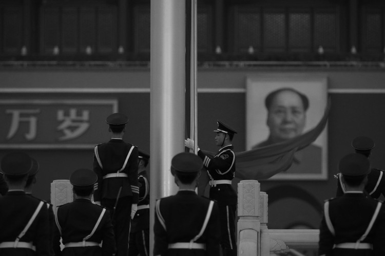 Um oficial da polícia paramilitar recolhe a bandeira da República Popular da China na frente do retrato de Mao Tsé-Tung pendurado na Praça da Paz Celestial, em Pequim no dia 2 de março. A Televisão Central da China recentemente citou o pronunciamento de Mao de que estava disposto a ver centenas de milhões de chineses assassinados (Feng Li/Getty Images)