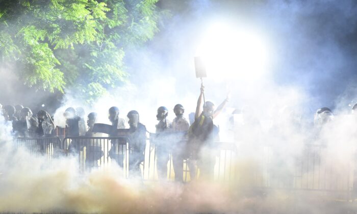 A fumaça sobe ao redor de um manifestante que levanta as mãos na frente de uma fila de policiais durante uma manifestação contra a morte de George Floyd em um parque perto da Casa Branca em Washington em 31 de maio de 2020 (Roberto Schmidt / AFP via Getty Images)