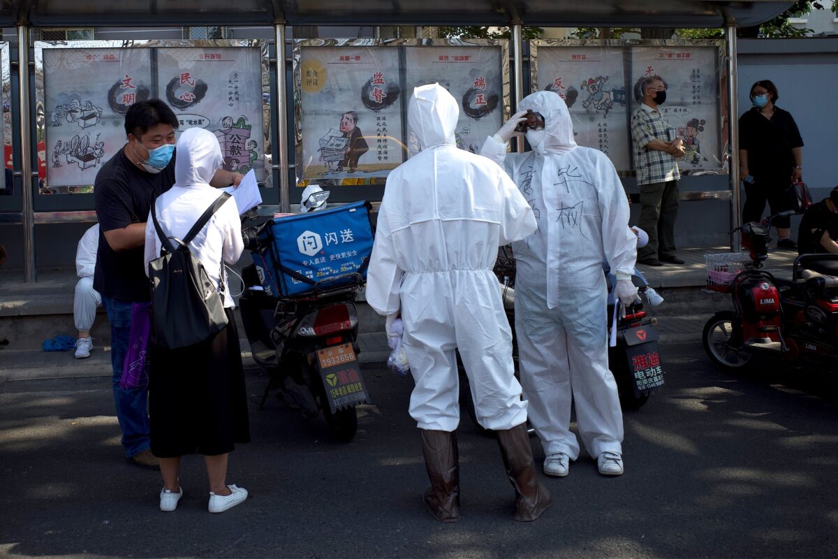 Membros da equipe médica com equipamento de proteção completo estão em frente ao Centro Esportivo de Guangan para ajudar as pessoas que moram perto ou visitaram o Mercado Xinfadi, um mercado atacadista de alimentos onde surgiu um novo grupo de Coronavírus COVID. 19, para testar em Pequim em 16 de junho 2020 (Noel Celis / AFP via Getty Images)