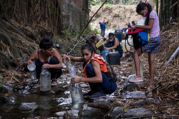 Fotografia de 26 de maio de 2020, onde é observado um grupo de pessoas coletando água em um riacho, em Caracas (Venezuela) (EFE / Miguel Gutiérrez)