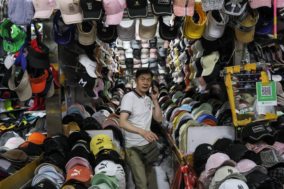 Um vendedor fala ao telefone em sua barraca cheia de bonés de marcas de luxo falsas em um mercado em Shenyang, China, em 1º de julho de 2020 (STR / AFP via Getty Images)