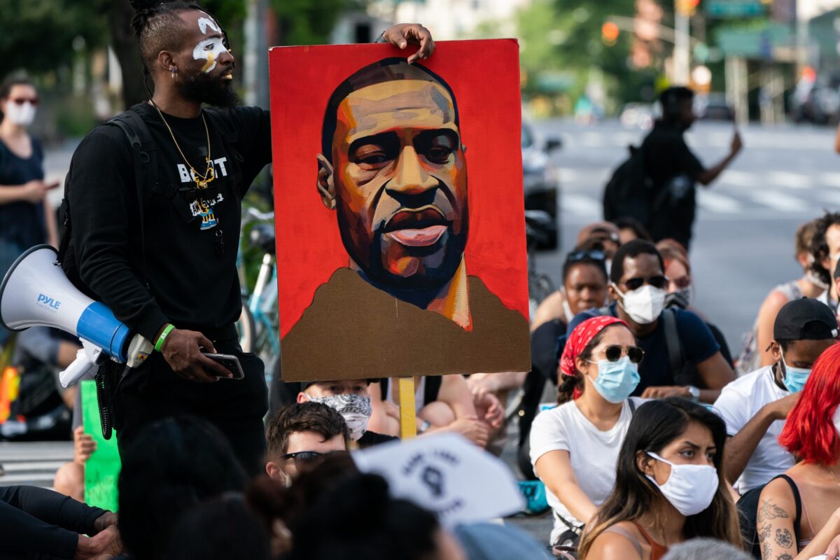 Um homem segura uma foto de George Floyd durante um protesto do Black Lives Matter na cidade de Nova Iorque em 18 de junho de 2020 (Jeenah Moon / Getty Images)