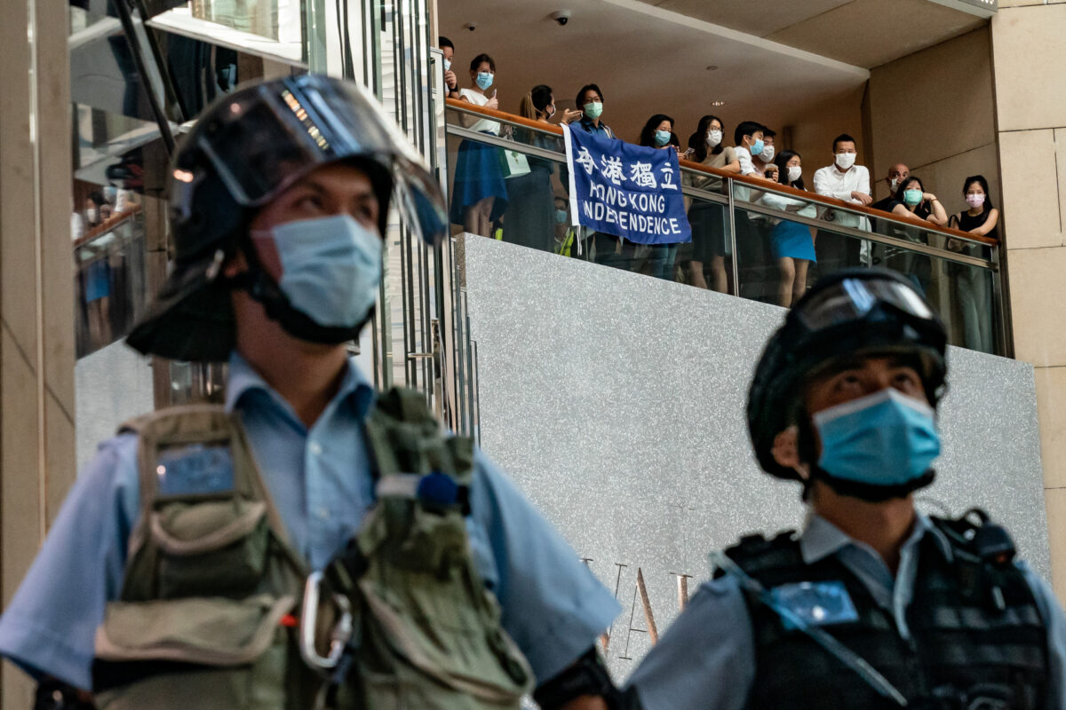 Apoiadores da democracia seguram uma bandeira da independência de Hong Kong e gritam slogans durante uma manifestação contra a lei de segurança nacional, enquanto a polícia de choque protege uma área em um shopping center em Hong Kong em 30 de junho de 2020 (Anthony Kwan / Getty Images)