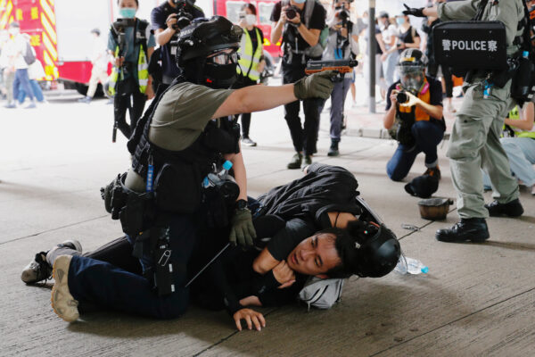 Um policial levanta sua pistola de spray de pimenta enquanto detém um homem durante uma marcha contra a lei de segurança nacional no aniversário da entrega de Hong Kong à China da Grã-Bretanha em Hong Kong, em 1º de julho de 2020 (Tyrone Siu / Reuters)