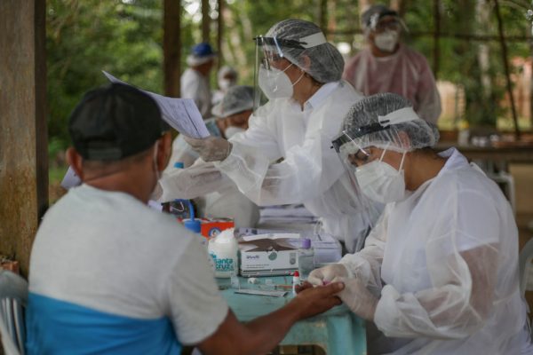 Uma enfermeira realiza teste COVID-19 em morador da comunidade ribeirinha de Belavista do Jaraqui, no rio Negro, a uma hora de barco de Manaus, em 29 de maio de 2020 no Brasil (Andre Coelho / Getty Images)