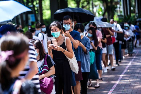 Uma mulher usa seu telefone enquanto espera para votar durante as eleições primárias em Hong Kong em 12 de julho de 2020 (Isaac Lawrence / AFP via Getty Images)