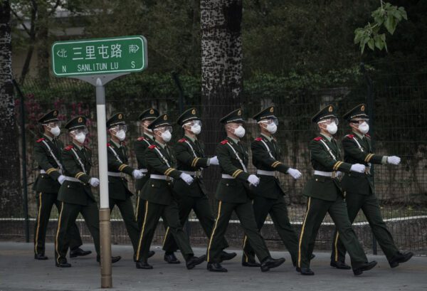 A polícia chinesa usa máscaras protetoras enquanto marcha para uma mudança de turno em Pequim em 14 de abril de 2020 (Kevin Frayer / Getty Images)