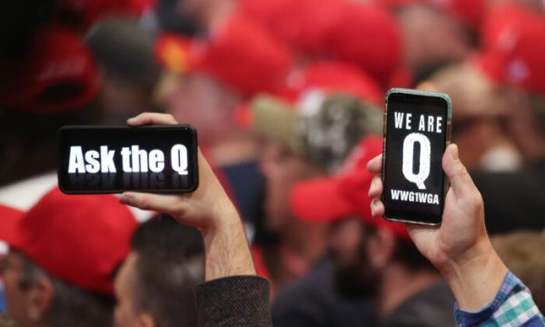 Pessoas seguram seus smartphones com mensagens relacionadas ao QAnon na tela em um comício em Las Vegas, Nevada, em 21 de fevereiro de 2020 (Mario Tama / Getty Images)