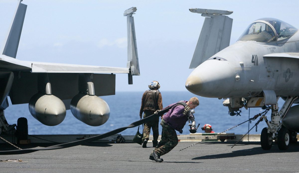 Um tripulante da Marinha dos EUA puxa um tubo de combustível pelo convés do porta-aviões USS Kitty Hawk (CV63) na Baía de Bengala, durante o exercício Malabar em 7 de setembro de 2007 (DESHAKALYAN CHOWDHURY / AFP via Getty Images )