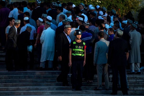 Uma foto tirada em 26 de junho de 2017 mostra um policial montando guarda enquanto os uigures chegam para a oração matinal de Eid al-Fitr na mesquita Id Kah em Kashgar, na região autônoma uigur de Xinjiang na China (JOHANNES EISELE / AFP / Getty Images)