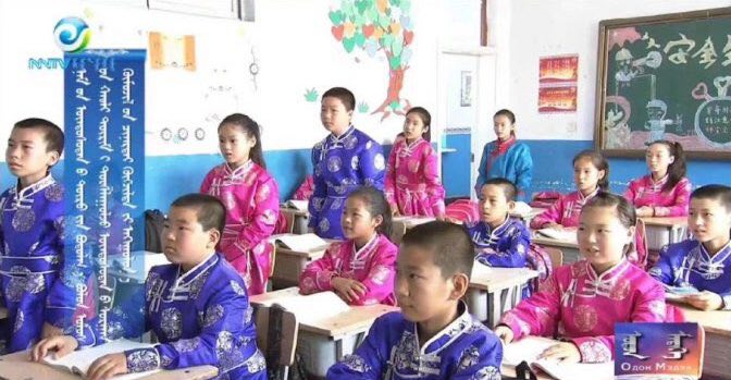 A mídia estatal mostra alunos vestidos com trajes tradicionais em uma sala de aula de uma escola primária na Mongólia Interior, que, segundo os moradores, foi encenada (Captura de tela)