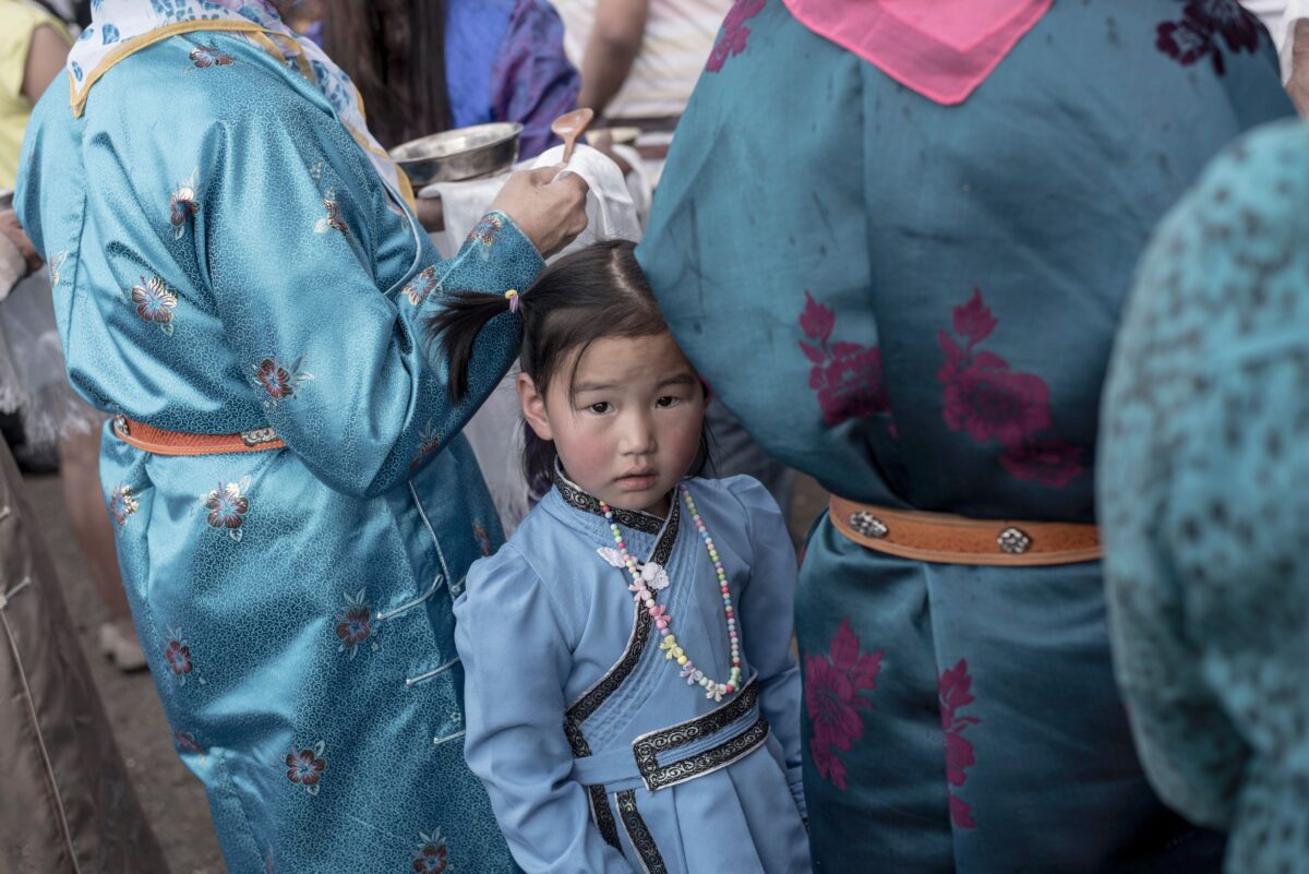 Uma garota vestida com um vestido tradicional da Mongólia espera com sua mãe durante o discurso do candidato às eleições presidenciais da Mongólia, Battulga Khaltmaa, do Partido Democrático da Mongólia, durante um comício em Ulan Bator, em 23 de junho de 2017 (Fred Dufour / AFP via Getty Images)