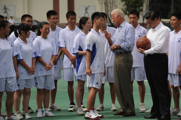 O então vice-presidente dos Estados Unidos, Joe Biden (centro-direita), fala com um estudante enquanto o vice-presidente chinês Xi Jinping (direita) assina uma bola de basquete na Dujiangyan Qingchengshan High School, nos arredores de Chengdu, no Província de Sichuan no sudoeste (China), em 21 de agosto de 2011 (PETER PARKS / AFP via Getty Images)