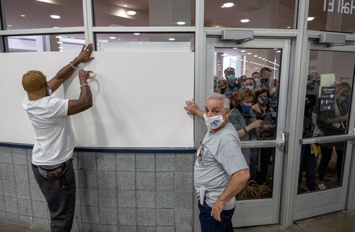 Eleitores cobrem as janelas para que os observadores não possam ver a área de contagem de votos no Centro TCF, onde as cédulas são contadas no centro de Detroit, 4 de novembro de 2020 (Seth Herald / AFP via Getty Images)