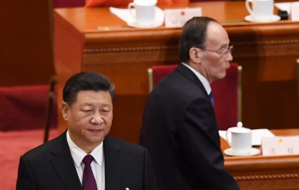 O líder da China Xi Jinping (à esquerda) se levanta enquanto Wang Qishan (à direita), ex-secretário da Comissão Central de Inspeção Disciplinar, chega à primeira sessão do PCC no 13º Congresso Nacional do Povo, em Pequim, em 17 de março de 2018 (GREG BAKER / AFP por meio do Getty Images)