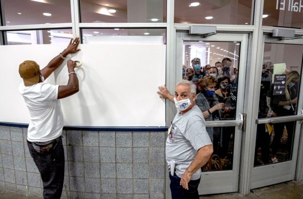 Eleitores cobrem as janelas da área de contagem de votos no TCF Center em Detroit, 4 de novembro de 2020 (Seth Herald / AFP via Getty Images)