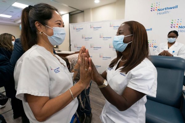 A enfermeira Annabelle Jimenez, à esquerda, parabeniza a enfermeira Sandra Lindsay após ser inoculada com a vacina COVID-19 em 14 de dezembro de 2020, no Long Island Jewish Medical Center no bairro de Queens, na cidade de Nova Iorque (Mark Lennihan - Pool / Getty Images)