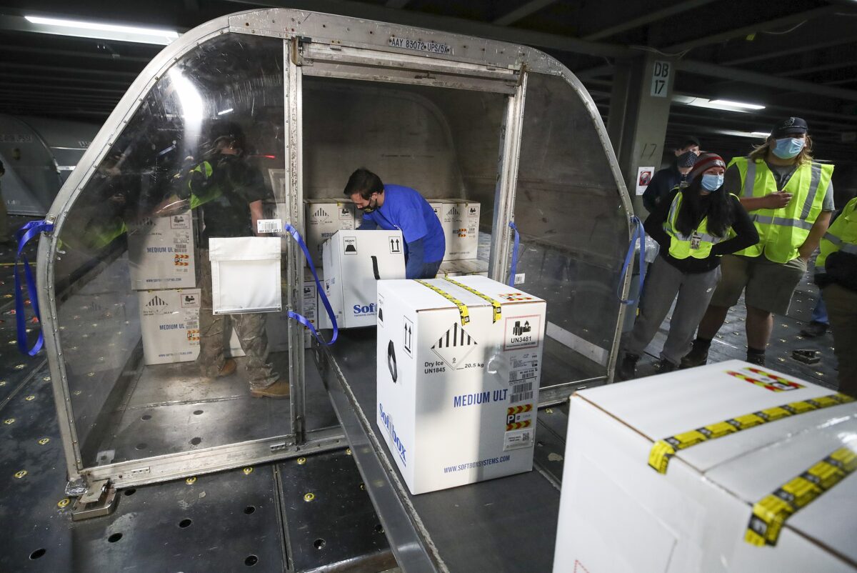 Caixas contendo as primeiras remessas de vacina Pfizer e BioNTech COVID-19 são descarregadas de contêineres de transporte aéreo no UPS Worldport em Louisville, Ky., Em 13 de dezembro de 2020 (Michael Clevenger / Pool / Getty Images)