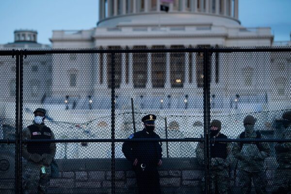 Um oficial da Polícia do Capitólio está com membros da Guarda Nacional atrás de uma cerca de controle de multidão ao redor do Capitólio um dia depois que um grupo invadiu o Capitólio dos EUA em Washington, em 7 de janeiro de 2021 (Brendan Smialowski / AFP via Getty Images)