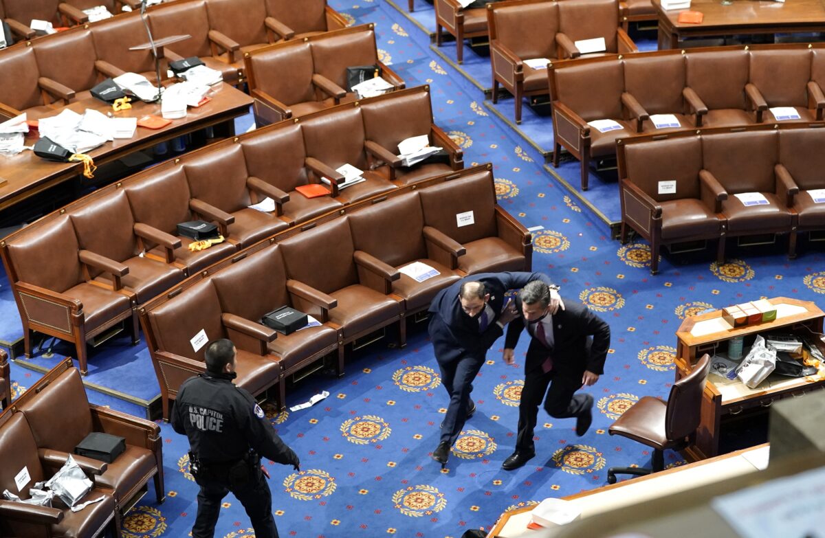 Membros do Congresso correm para se proteger enquanto os manifestantes tentam entrar na Câmara dos Representantes durante uma sessão conjunta do Congresso em Washington em 6 de janeiro de 2021 (Drew Angerer / Getty Images)