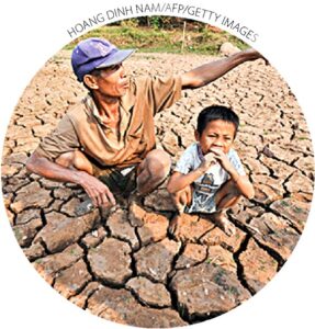 Um fazendeiro e seu filho sentam-se em seus campos de arroz atingidos pela seca no rio Mekong, fora de Vientiane, Laos, em 27 de março de 2010. Uma severa seca na região fez com que o Mekong caísse para o nível mais baixo em 50 anos. 