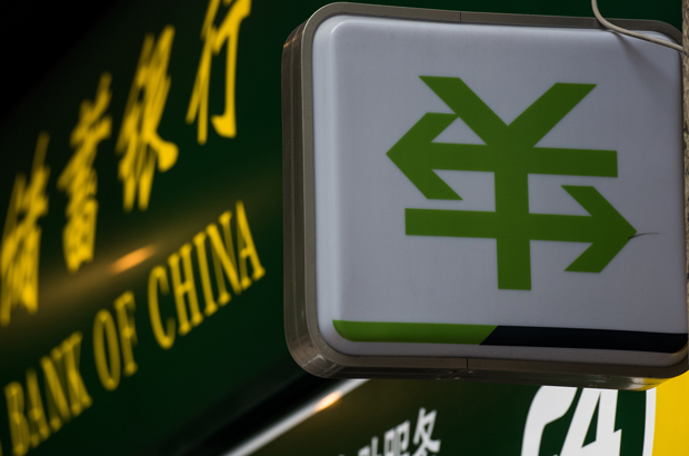 Um letreiro com o símbolo da moeda chinesa, o yuan ou renminbi, com duas flechas atravessando-o, em frente de uma filial do Banco da China em Xangai em 13 de agosto de 2015 (Johannes Eisele/AFP/Getty Images)