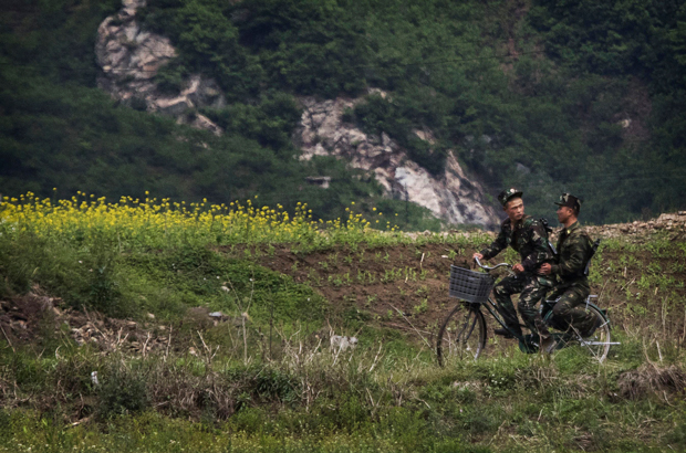 Soldados norte-coreanos numa bicicleta nas margens do rio Yalu, na cidade fronteiriça de Sinuiju, Coreia do Norte, em 23 de maio de 2017. (Kevin Frayer/Getty Images)